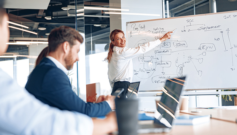 businesswoman-explaining-her-business-plan-to-colleagues-while-making-a-presentation-in-the-office